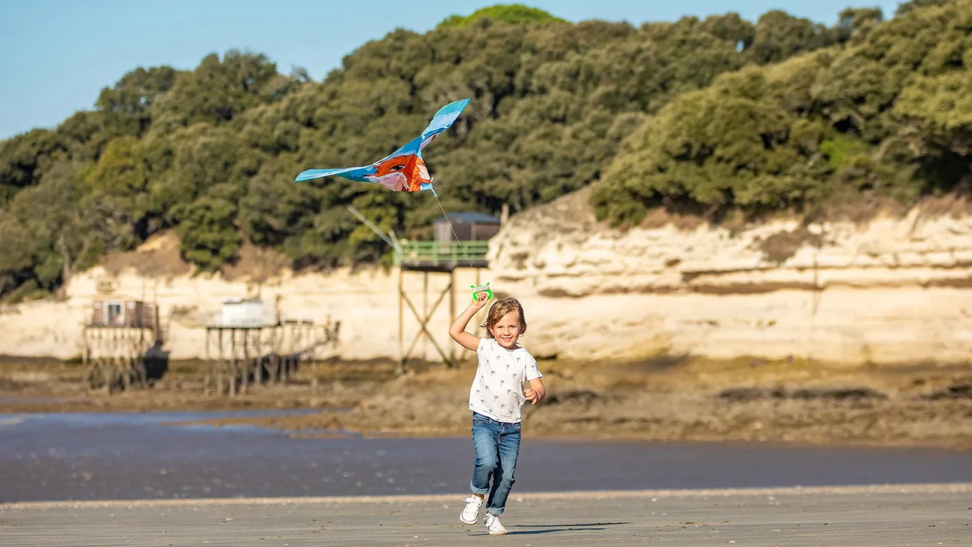 Enfant sur la plage avec un cerf-volant au printemps